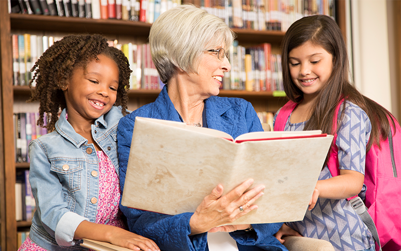 Woman reading a book to children